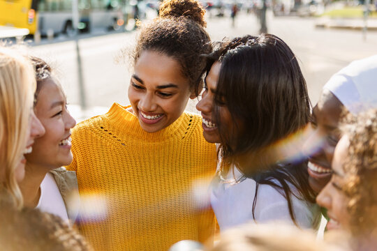 Diverse young women smiling together outdoors in the city. Multiracial female friends enjoying time together and sharing positive energy. Community and friendship concept.