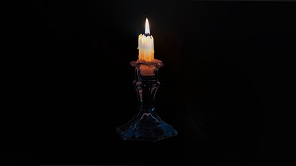 Close up of a burning candle on black background. Horizontal image.