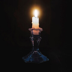 Close up of a burning candle on black background. Horizontal image.