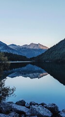 Calm lake reflecting mountains at dawn