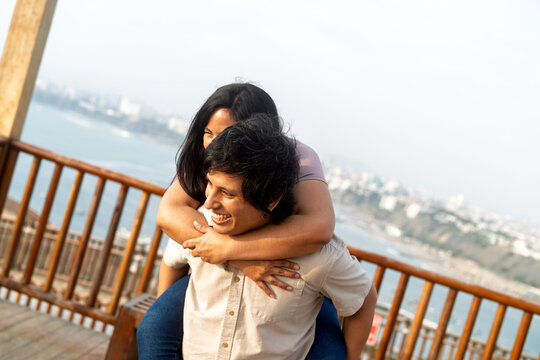 Young couple enjoying piggyback ride at city viewpoint