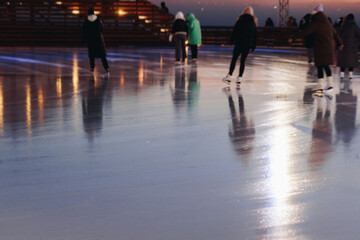Ice skating on the ice rink arena with people, skating rink surface, ice skating in winter city, winter activities, holiday christmas time, with new year decoration and illumination, ice skates boots