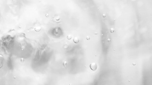 Close-up of water bubbles rising in fluid motion on a light gray backdrop. Air bubbles scatter through soft currents, forming an ethereal underwater abstraction full of life
