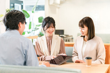 Businessmen and businesswomen discussing business at a table in a business meeting space
