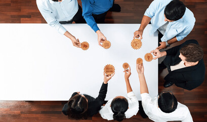 Aerial view of a diverse team of business professionals engaging in a collaborative strategy session with gears on a table, symbolizing teamwork and innovation in the workplace. Amity