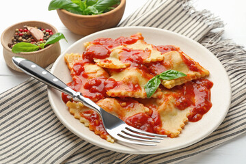 Delicious ravioli with tomato sauce and basil served on white wooden table, closeup