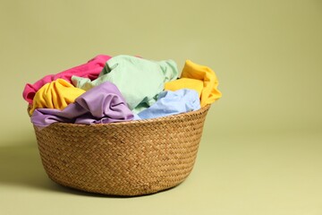 Laundry basket with clothes against olive background. Space for text