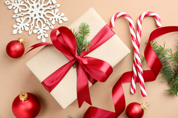 Fir tree branches, gift, candy canes and Christmas decor on beige background, flat lay