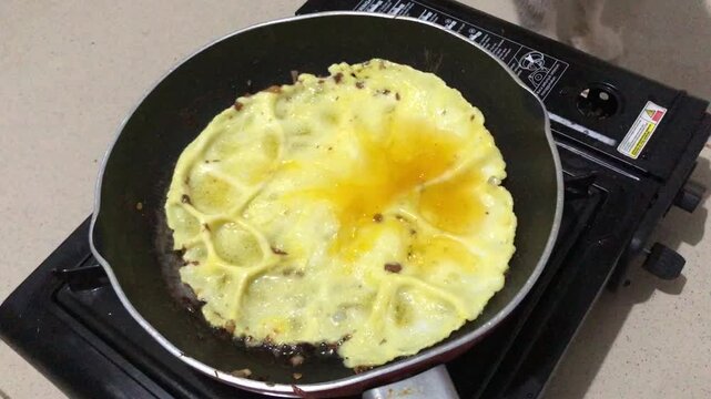 Cooking an omelet in a frying pan on a gas stove