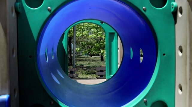 POV shot moving through a playground tunnel, revealing colorful play structures in a public park in Asuncion, Paraguay. Ideal for kids activities, outdoor fun, and recreation themes.