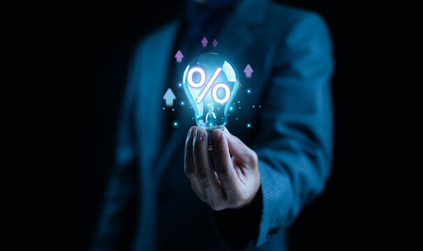 Businessman holding glowing light bulb with percentage symbol representing financial innovation interest rate and investment growth idea. Concept for finance, business creativity, and digital economy. - Powered by Adobe