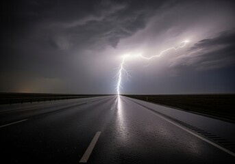 Powerful lightning bolt striking down onto a wet, dark interstate highway during a severe thunderstorm