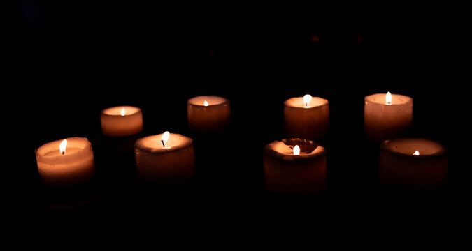 Velas encendidas en la oscuridad creando atm&oacute;sfera &iacute;ntima y espiritual