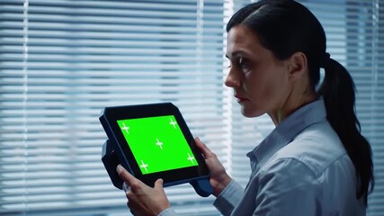 Female scientist or researcher holding a tablet with a green screen looking at data or a presentation in a modern laboratory or office setting ready for chroma key compositing. - Powered by Adobe