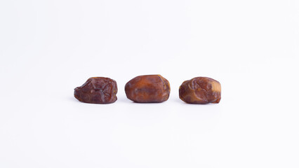 Three Succulent Sukkari Dates on White Background. Sweet, nutritious fruit for healthy snacks, Ramadan, or gourmet dessert ingredient.
