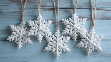 White snowflakes hanging from a string against a blue wooden background.