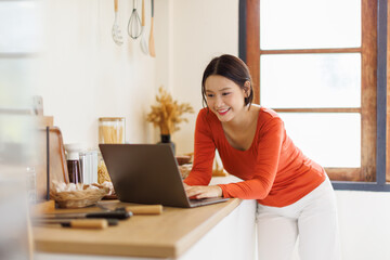 Asian woman in a kitchen using laptop at home
