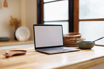 Open laptop with blank screen on a wooden desk in a kitchen room home office. Social media culinary concept, 
