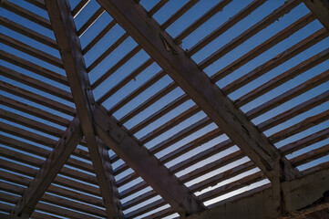 Old and Tattered Wood Roof Frame with Blue Sky Overhead.