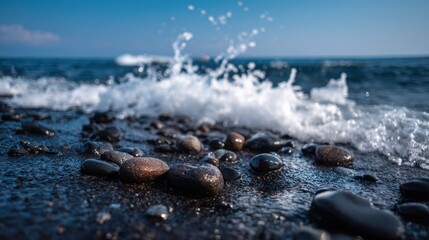 A rocky beach with pebbles and waves, under a clear blue sky with a few clouds.