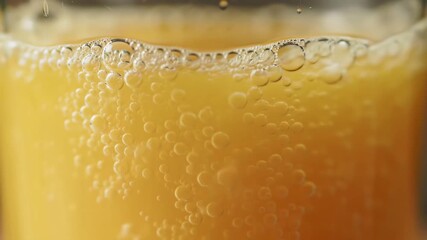 Closeup of effervescent bubbles rising in a golden liquid creating a foamy head perfect for illustrating refreshing beverages or carbonated drinks. - Powered by Adobe