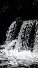 Cascading water falls over a small wall, creating a beautiful, dynamic scene