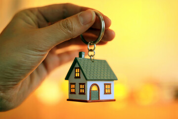 Hand Holding House Keychain Symbolizing Real Estate Ownership and Home Investment