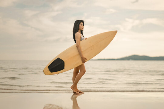Sexy woman holding surfboard sport related to surfing vacations healthy living and active beach lifestyle.