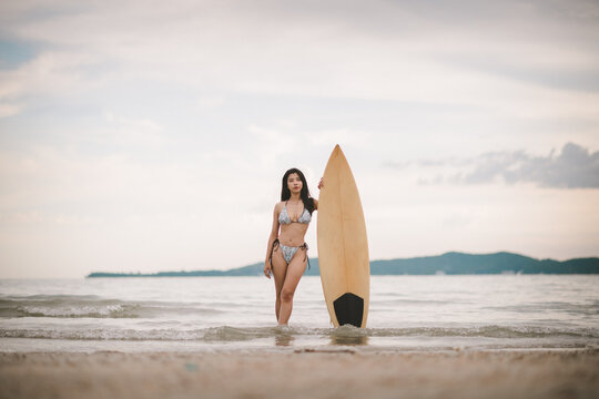 Sexy woman holding surfboard sport related to surfing vacations healthy living and active beach lifestyle.