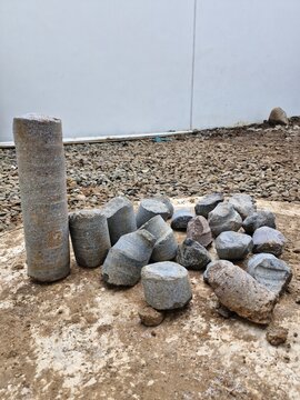 cylindrical granite rock core sample and broken pieces on the dirt ground of a construction site.