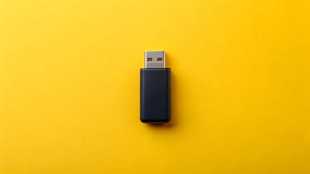 Tiny black U S B flash drive with silver connector isolated on bright yellow background USB flash drive