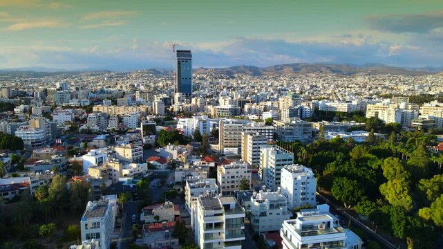 Aerial panoramic view of Limassol, Cyprus, highlighting the modern skyline, residential areas, and green spaces. The image captures the vibrant city life, urban development.
