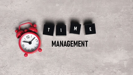 Time Management concept text with small red alarm clock and letter blocks on textured grey background