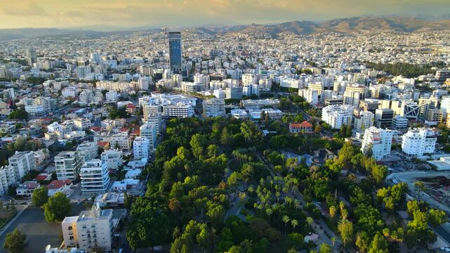 Aerial panoramic view of Limassol, Cyprus, highlighting the modern skyline, residential areas, and green spaces. The image captures the vibrant city life, urban development.