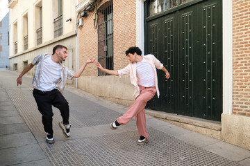 Two male dancers connecting hands, expressing art on a city street