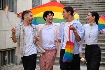 Group of diverse young people joyfully participating in an LGBTQ plus pride celebration, holding rainbow flags