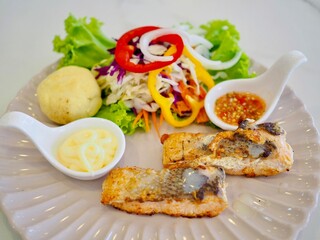 Salmon steak and vegetable salad with salad dressing and seafood sauce placed on a plate. Healthy food.