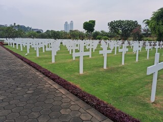 Ereveld Ancol war cemetery in Jakarta, Indonesia, with neatly arranged white gravestones surrounded by green lawns and trees, creating a solemn and peaceful memorial atmosphere.