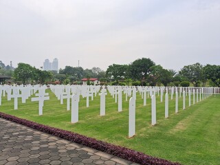
Ereveld Ancol war cemetery in Jakarta, Indonesia, with neatly arranged white gravestones surrounded by green lawns and trees, creating a solemn and peaceful memorial atmosphere.