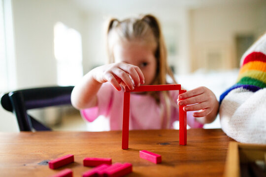 Young girls building colourful rectangular blocks on the table