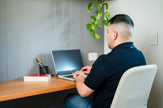 A man working at his home office desk on laptop - Powered by Adobe
