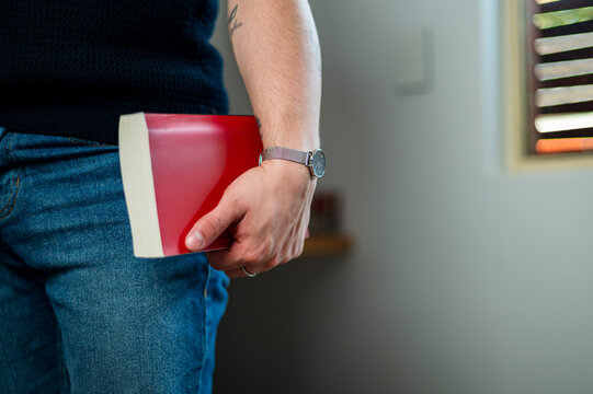 A man in his 30s with a book while enjoying his home office, showcasing a relaxed lifestyle.