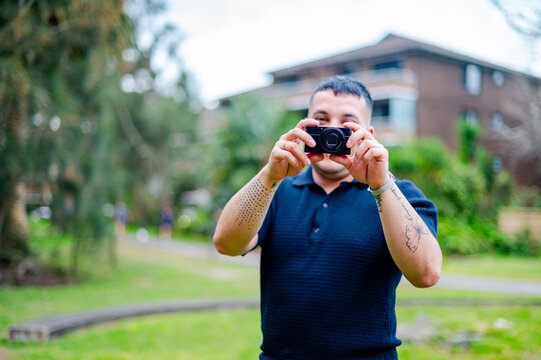 A man enjoys taking pictures in a park filled with greenery