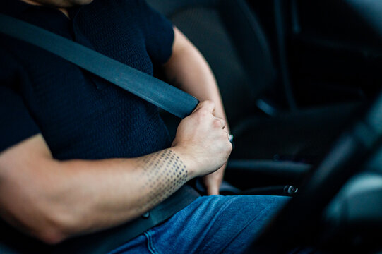 Adult male secures himself with a seatbelt inside a vehicle while preparing to drive
