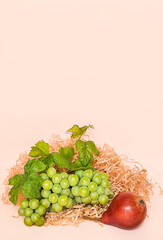Green grapes and red pear on a beige background, composition