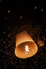 hundreds of paper lanterns glowing in the night sky during yi peng festival in chiang mai, thailand, as warm flames lift them gently, symbolizing wishes and letting go.