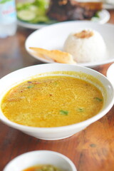 Traditional Indonesian soto lamongan served in a bowl, featuring rich yellow broth, shredded chicken, vermicelli, and fresh herbs.