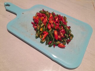 Large curly chilies that have been thinly sliced ​​with a sharp knife on a blue plastic...