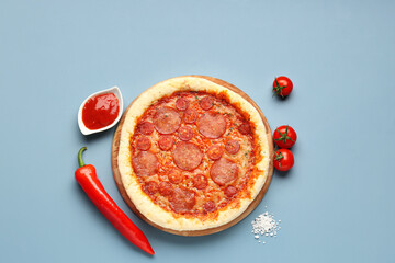 Delicious pepperoni pizza, tomatoes, jalapeno pepper and sauce on blue background