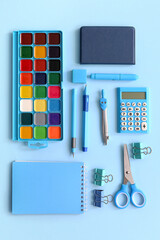 Different school stationery and notebooks on blue background